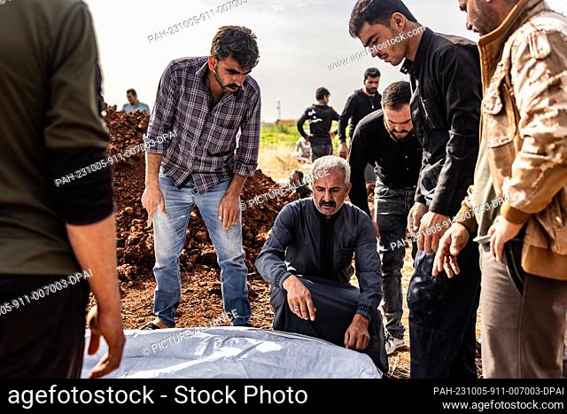 05 October 2023, Syria, Aleppo: People bury the victims of the missile strike that targeted a civilian home in the town of Kafr Nouran in Aleppo