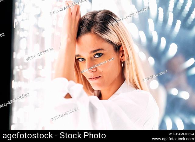 Attractive blond woman leaning on illuminated glass wall