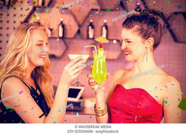 Composite image of female friends toasting a glass of cocktail in bar