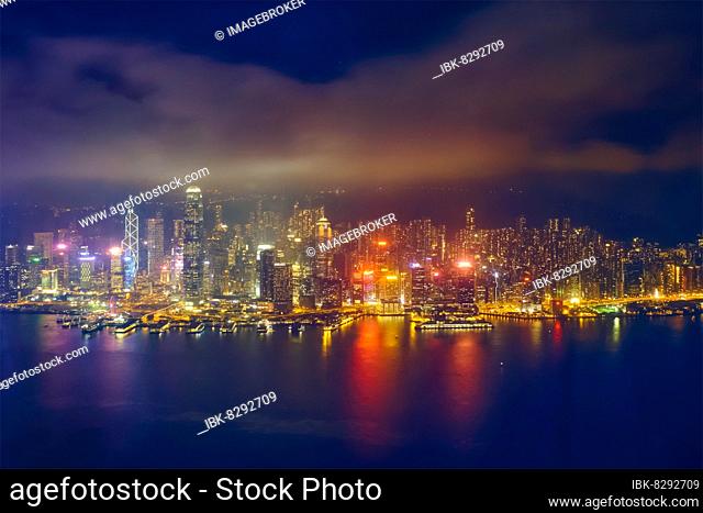 Aerial view of illuminated Hong Kong skyline cityscape downtown skyscrapers over Victoria Harbour in the evening. Hong Kong, China, Asia