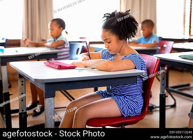 African american girl studying while sitting on her desk in the class at school