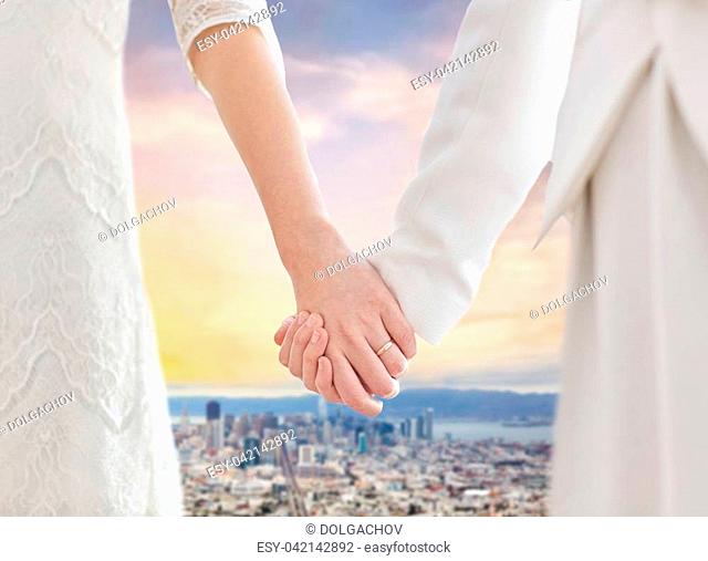 gay, same- marriage and homosexual relationships concept - close up of happy married lesbian couple with flower bunch over san francisco city view background