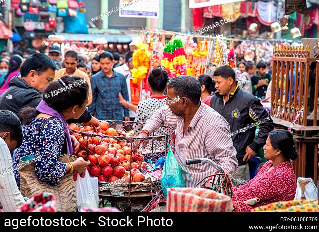 Bhaktapur, Nepal - October 19, 2014: A fruit seller with customers in the historic city centre