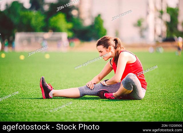 Theme sport and health. Young beautiful Caucasian woman sitting doing warm-up, warming up muscles, stretching green grass