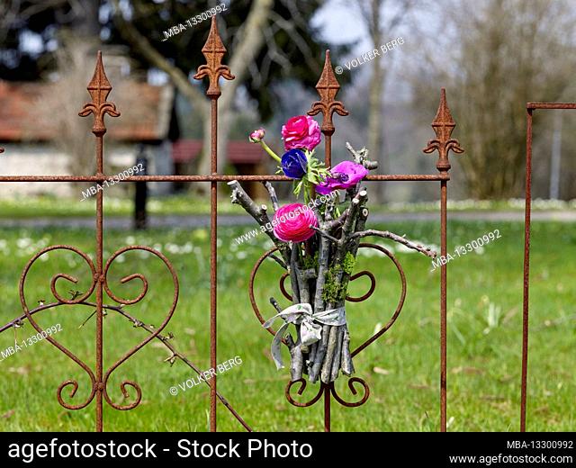 Easter wreaths made of ranunculus, blue anemone and fruit tree branches on an old wrought iron fence