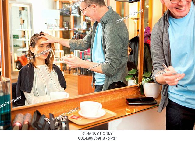 Male hairdresser advising female customer in hair salon