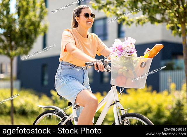 woman with food and flowers in bicycle basket