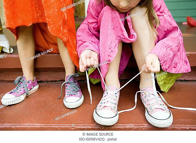 Two girls, one tying up shoelace