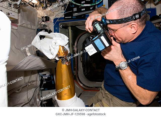 In the International Space Station's Destiny laboratory, NASA astronaut Don Pettit, Expedition 30 flight engineer, uses a still camera to photograph an arm of...