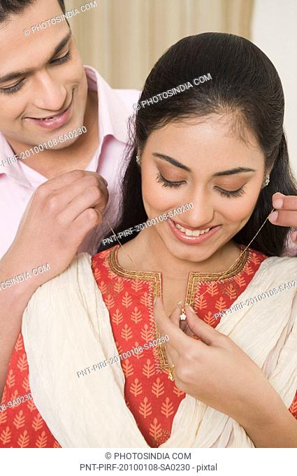 Man putting a necklace on a woman's neck
