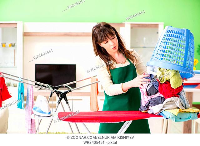 Young woman ironing clothing at home