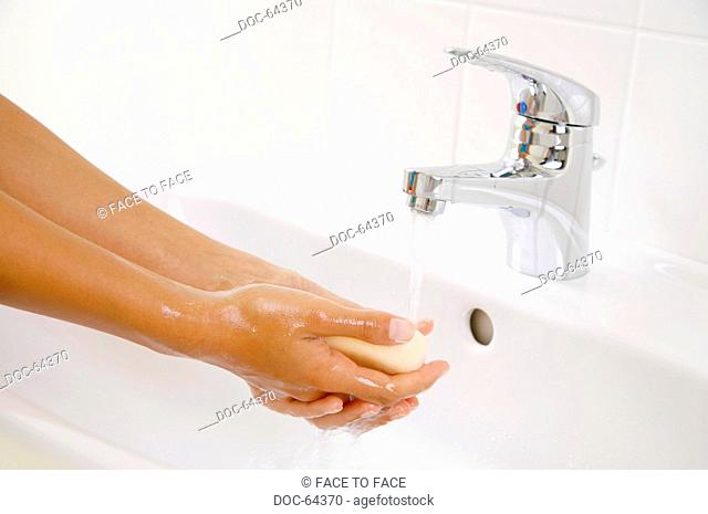 Woman washing hands with bar of soap in sink - close-up
