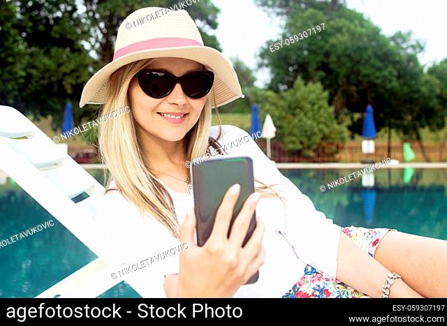 The attractive blond hair woman is using phone and making selfie about herself outdoors