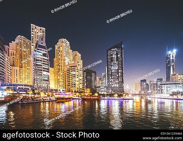 Dubai Marina Port, UAE, United Arab Emirates - Night view of high-rise buildings of residential district in Dubai Marina And Tourist Boat
