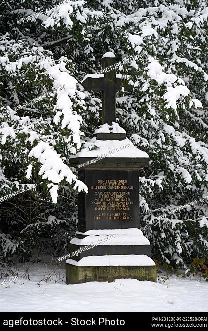 06 December 2023, Hamburg: Snow lies beneath the trees and the memorial stone for the founders of the Eilbek community center in Jacobipark