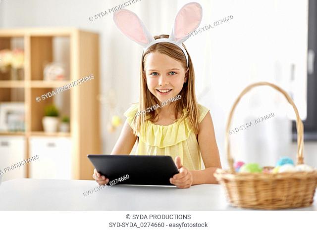 happy girl with tablet pc and easter eggs at home
