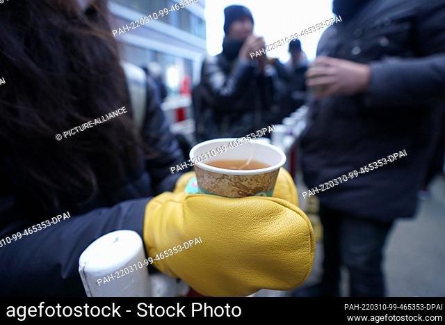 10 March 2022, Hamburg: A Ukrainian woman drinks a cup of tea in the queue in front of the Central Aliens Office with the new registration office in the Office...