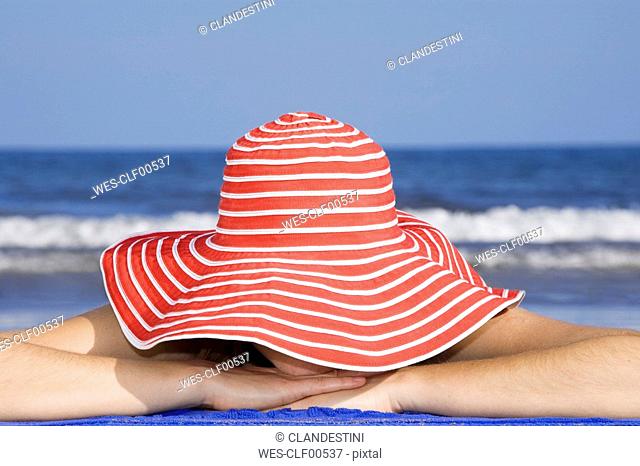 Woman with hat, lying on beach