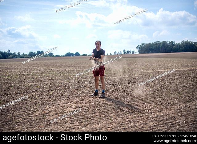 07 September 2022, North Rhine-Westphalia, Detmold: Ulf Allhoff-Cramer stands in his field and lets dust-dry earth trickle through his fingers