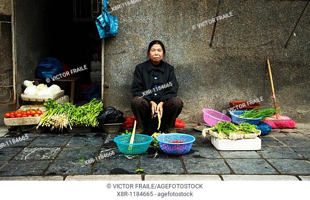 An elderly Chinese woman sells vegetables in a street market at central Guilin, south China