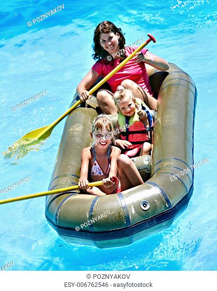 Family with children ride rubber boat at swimming pool