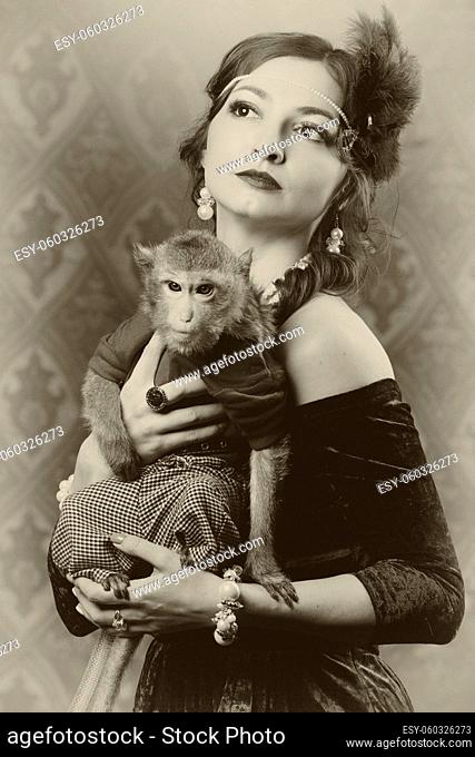 Retro female portrait in the style of 20s or 30s. A gorgeous lady is holding a little monkey. Photo in vintage style