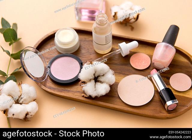 makeup, perfume and cosmetics on wooden tray