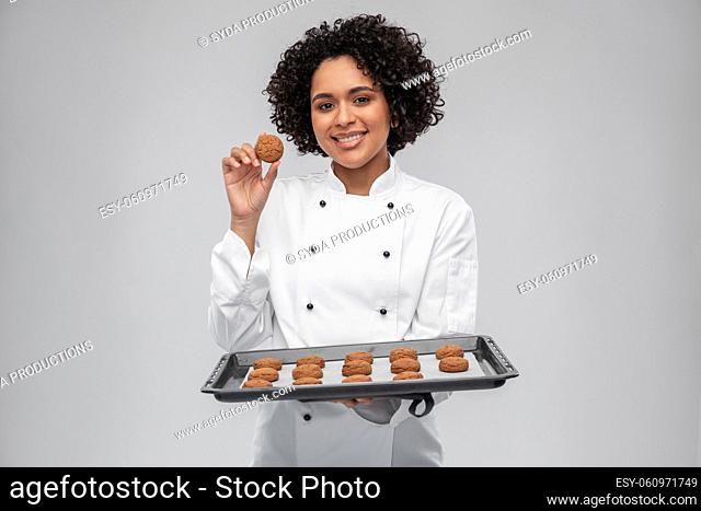 happy female chef with cookies on oven tray