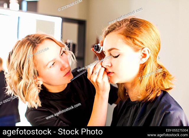 Professional visagist working with beautiful young woman. The process of applying makeup
