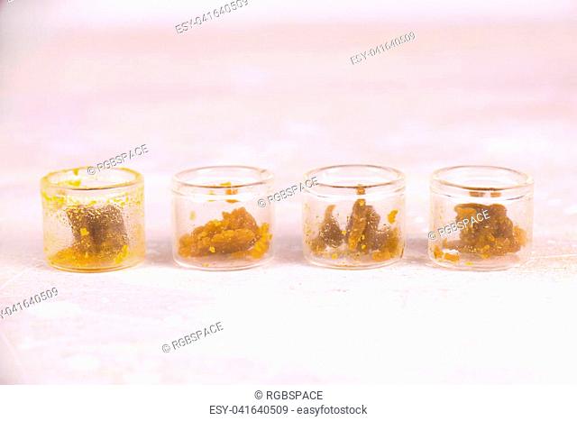 Macro detail of assorted marijuana extraction concentrate aka wax crumble on jars isolated on white background
