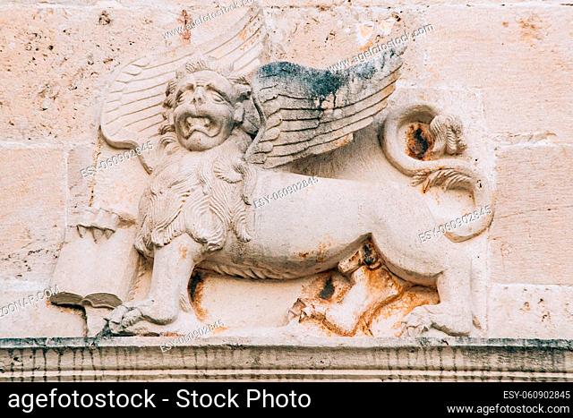 A bas-relief on the wall depicting a mythical lion with wings and a book in its paws. High quality photo