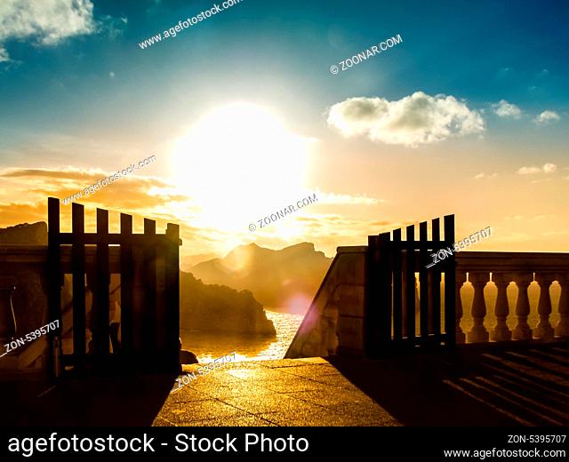 Amazing scenic landscape with an open gate to mountain range and watercourse, at sunrise, symbol of freedom and heaven