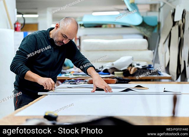 Craftsman measuring fabric at workbench in workshop
