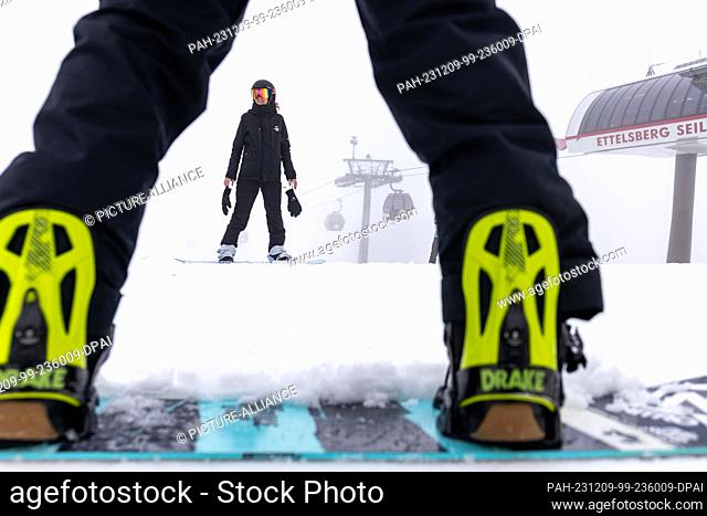 09 December 2023, Hesse, Willingen: Snowboarders get ready for the descent after arriving at the Ettelsberg cable car mountain station at an altitude of 830...