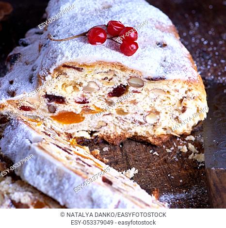 Traditional European Christmas pastry, home baked stollen with spices and dried fruit. Sliced on rustic brown wooden table