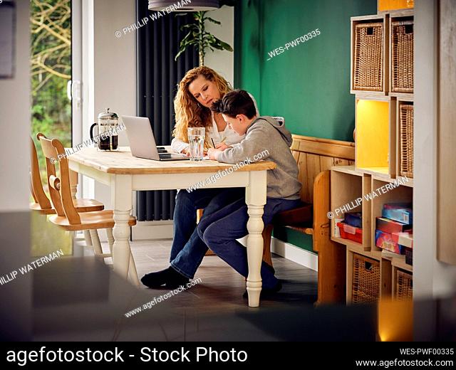 Mother teaching son at home in front of laptop at home