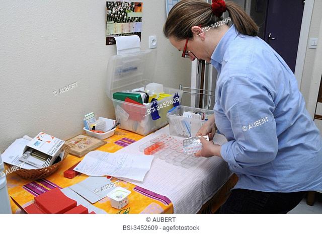 Independent nurse, in Vénissieux, France. Independent nurse at the home of a diabetic patient of type 1. The nurse prepare the pill box of the patient