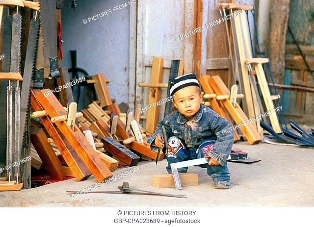 China: Apprentice Uighur carpenter in his father's workshop, Yarkand, Xinjiang Province