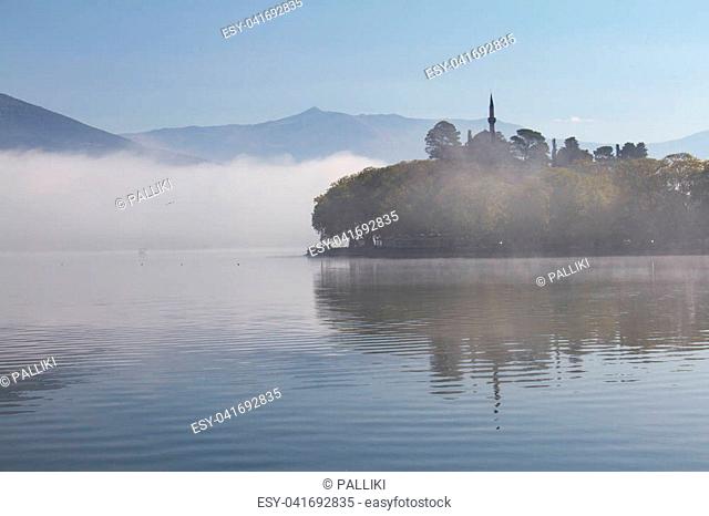 Atmospheric scene of Lake Pamvotis on a misty morning in Ioannina, Greece, with Aslan Pasha mosque in the background