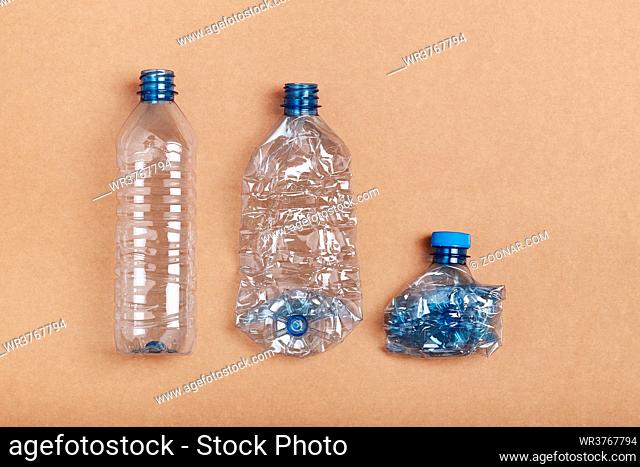 Squashed empty plastic bottles put in a row, over cardboard background. Collecting plastic waste to recycling. Concept of plastic pollution and too many plastic...