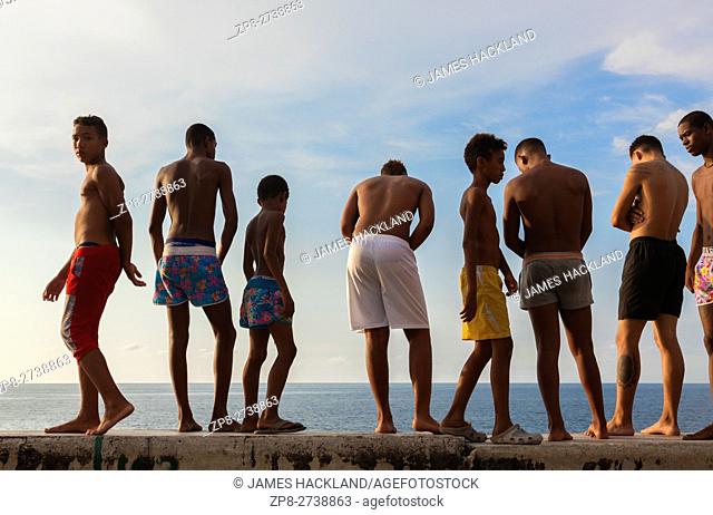 Kids in their bathing suits standing along the seawall about to go swimming along the Malecón (Avenida de Maceo) in Central Havana, Cuba