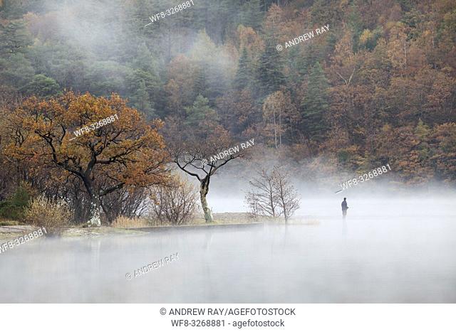 A fisherman near the north end of Crummock Water in the Lake District National Park, captured using a telephoto lens on a still misty morning in late October