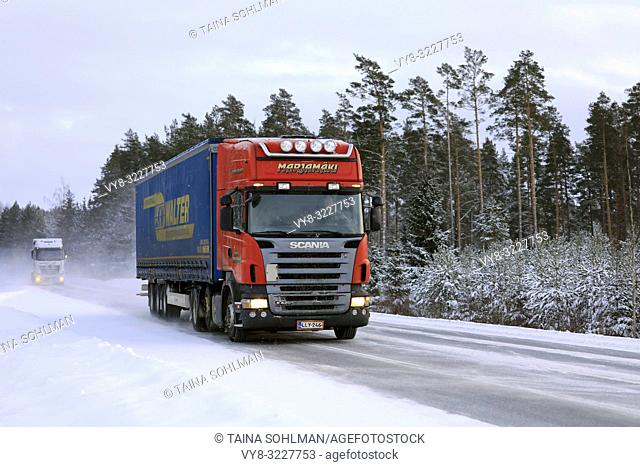 Salo, Finland - January 18, 2019: Red Scania R420 semi trailer Marjamaki and another truck drive on snowy winter highway in South of Finland