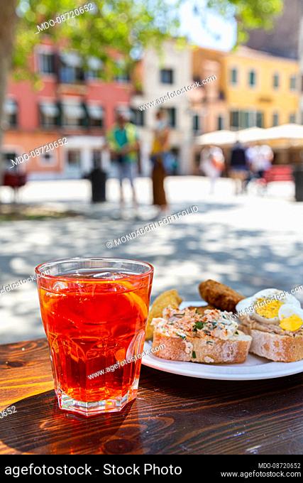 Glass with Spritz aperitif and Cicchetti dish, typical Venetian appetizers based on fish or cured meats served on a slice of bread or polenta