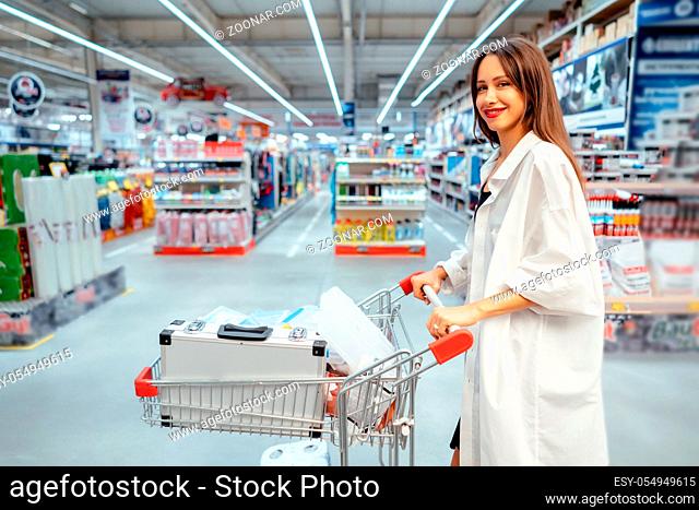 happy young woman pushing trolley in supermarket blur background