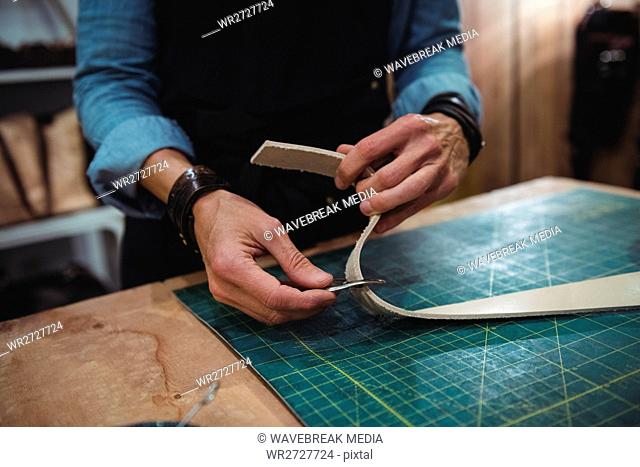 Mid-section of craftswoman cutting leather