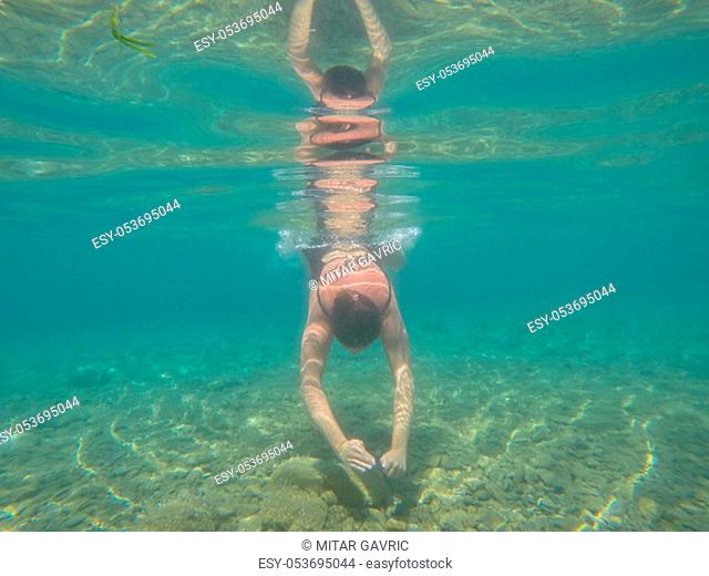 Underwater scene of woman jumping in the sea. Summer holiday fun