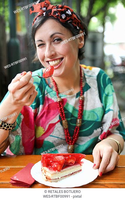 Woman eating strawberry cake in street cafe