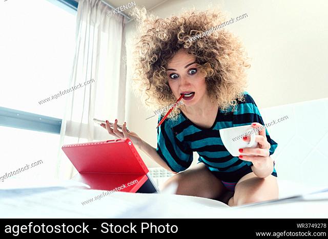 Woman student on her bed learning for exam in panic and despair