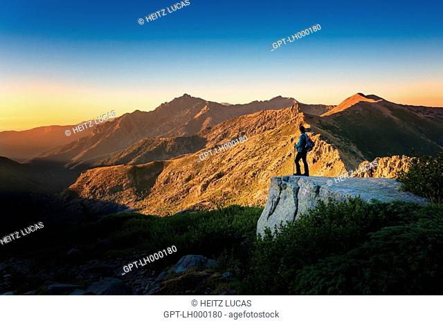 HIKER CONTEMPLATING THE CORSICAN MOUNTAINS AT SUNRISE, PETRA PIANA REFUGE, GR20 NORTH, UPPER CORSICA, FRANCE, FRANCE
